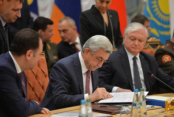 President Serzh Sarkisian signs a document as Armenia;s Foreign Minister Edward Nalbandian (right) and Defense Minister Vigen Sargsyan look on