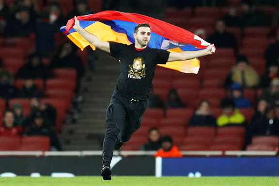 An Armenian rushes the field with an Artsakh flag after Arsenal beats the Azerbaijani soccer team, Qarabag