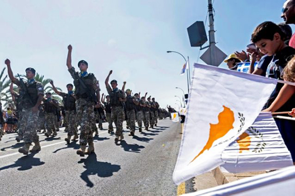 People in Nicosia wave flags during a military parade marking the 59th anniversary of Cyprus' independence from British colonial rule in October 2019 (AFP Photo/Iakovos Hatzistavrou)